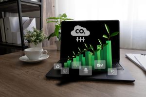Laptop displaying green growth chart with plants symbolizing sustainability and eco-friendly business development on a desk with a coffee cup.
